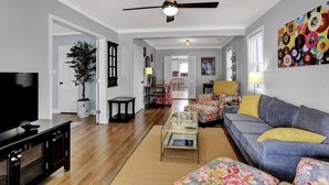 A living room with a television, sofa, coffee table, and a ceiling fan. - Christian Brothers Getaway (Memphis)