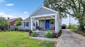 A single-story house with a blue front door, number 245, and a small porch with steps leading to the entrance. - Christian Brothers Getaway (Memphis)