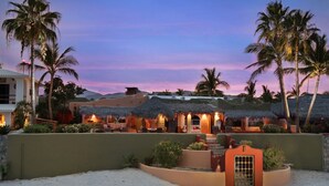 Ein Resort mit strohgedeckten Häusern, Palmen und einem Sandstrand.