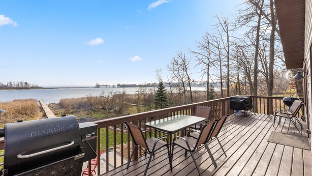 A wooden deck with a grill, table, and chairs overlooking a lake. - LAKE HOME ON PELICAN!! Just a short walk away from food, live music, & golf! (Breezy Point)