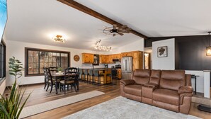 A modern kitchen with wooden cabinets, a dining area with a table and chairs, and a living room with a leather sofa. - LAKE HOME ON PELICAN!! Just a short walk away from food, live music, & golf! (Breezy Point)