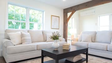 A living room with a beige sectional sofa, a black coffee table, and a vase with flowers.