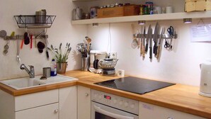 Une cuisine équipée d’un évier, d’une cuisinière et de divers ustensiles accrochés au mur.