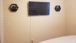 Ein Zimmer mit einem Wand-Flachbildfernseher, zwei sechseckigen Wanddekorationen und einer Steckdose an der linken Wand.