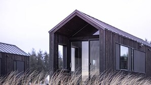 Un edificio moderno de madera oscura con techo inclinado y ventanas amplias.