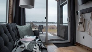 Una habitación moderna con sofá, una zona de lectura, un ventanal y vistas al exterior.