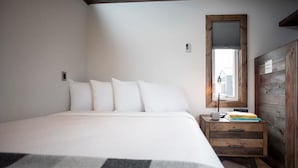 Un dormitorio con una cama grande, una mesita de noche de madera, un espejo y una ventana.