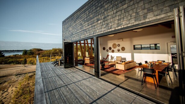 Ein modernes Haus mit einer Terrasse mit Blick auf ein Gewässer.