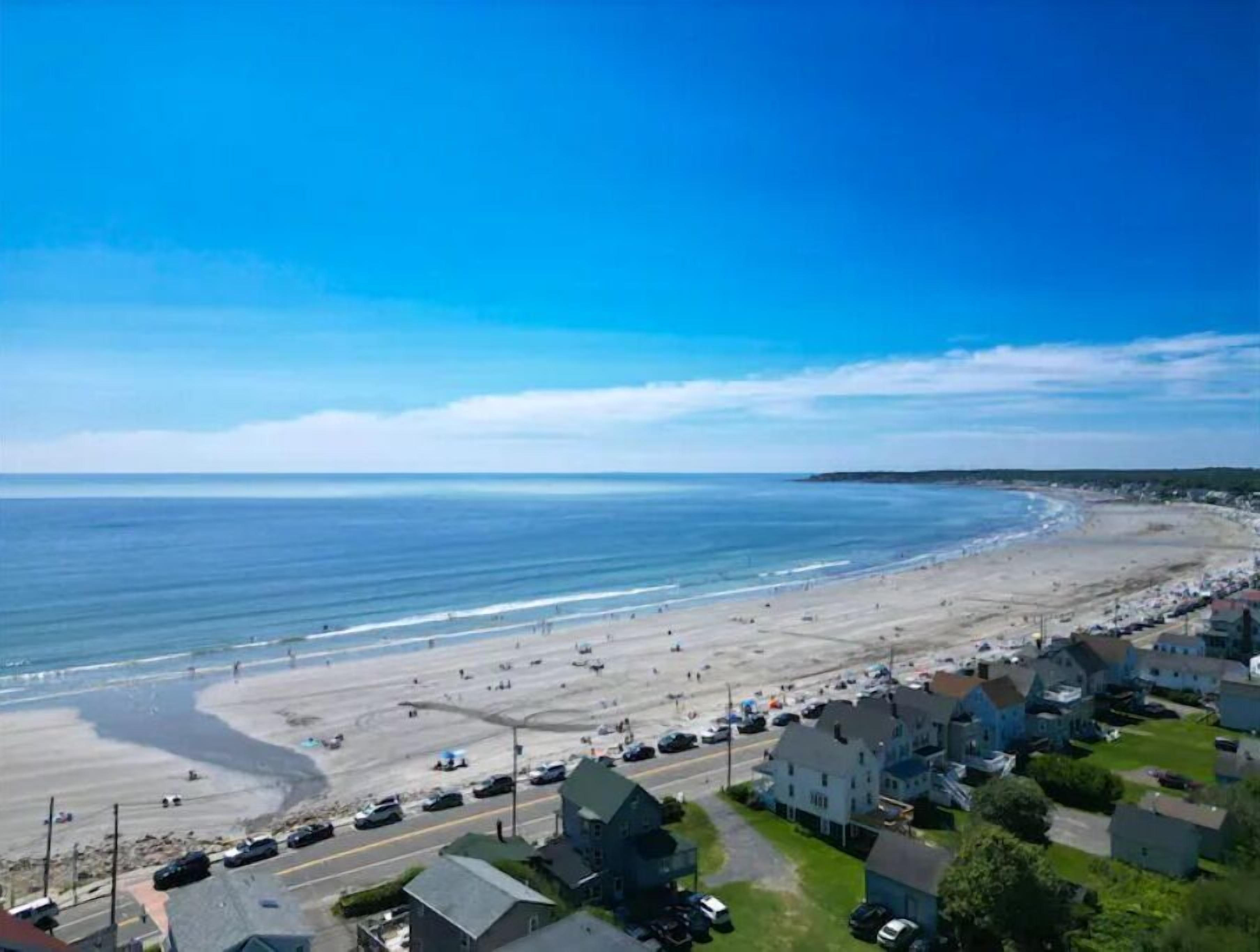 A coastal town with a beach, houses, and a road.