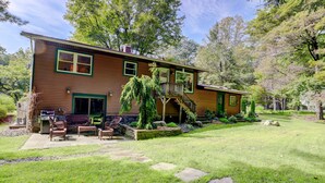 A two-story wooden house with a covered patio and outdoor seating. - Mid-Century Modern House Convenient to All that Woodstock has to Offer. (Woodstock)