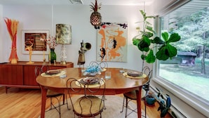 A dining area with a wooden table, chairs, and a hanging pineapple light fixture. - Mid-Century Modern House Convenient to All that Woodstock has to Offer. (Woodstock)