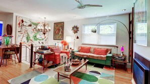 A living room with a sofa, coffee table, and a dining area with chairs and a table. - Mid-Century Modern House Convenient to All that Woodstock has to Offer. (Woodstock)