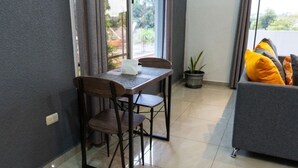 A dining area with a table and chairs, a potted plant, and a grey sofa with yellow cushions. - Modern Apartment in La Ceiba ‼️No Cleaning Fee‼️ (La Ceiba)
