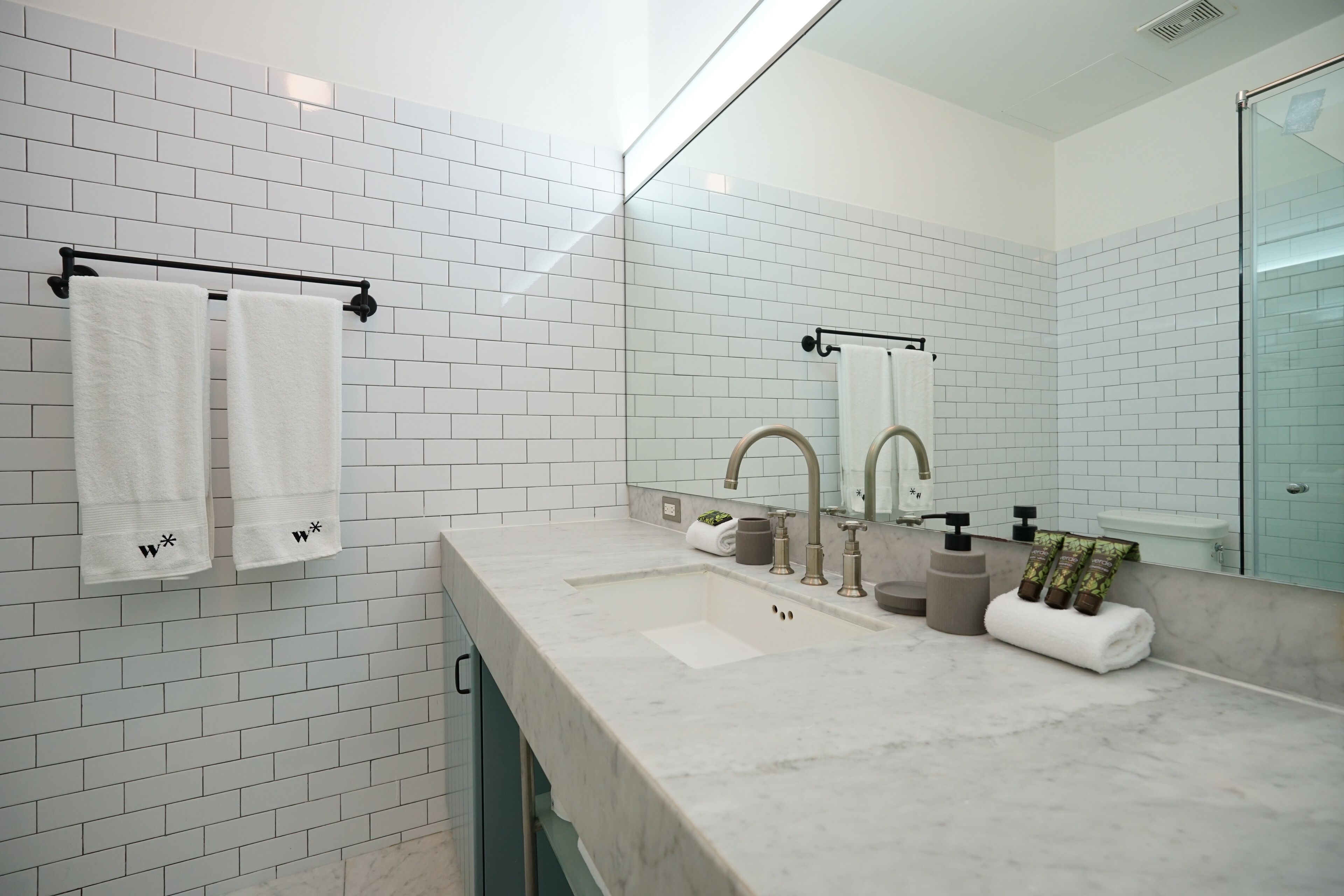 A modern bathroom with white subway tiles, a marble sink, and a large mirror.