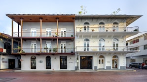 A multi-story building with balconies, a wooden facade, and a sign for 'Casa Mallet'.