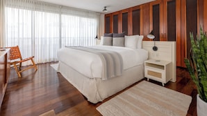 A bedroom with a large bed, wooden paneling, a desk, and a chair.