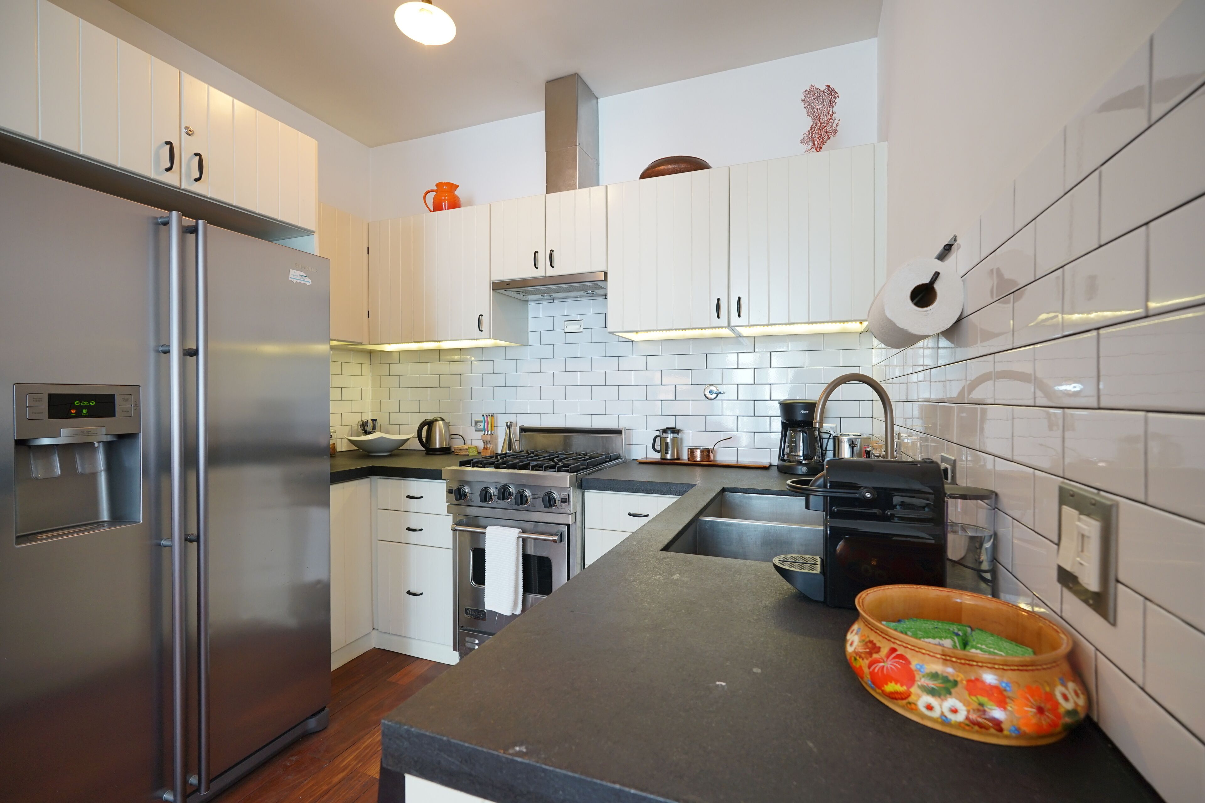 A modern kitchen with stainless steel appliances, white cabinets, and a black countertop.
