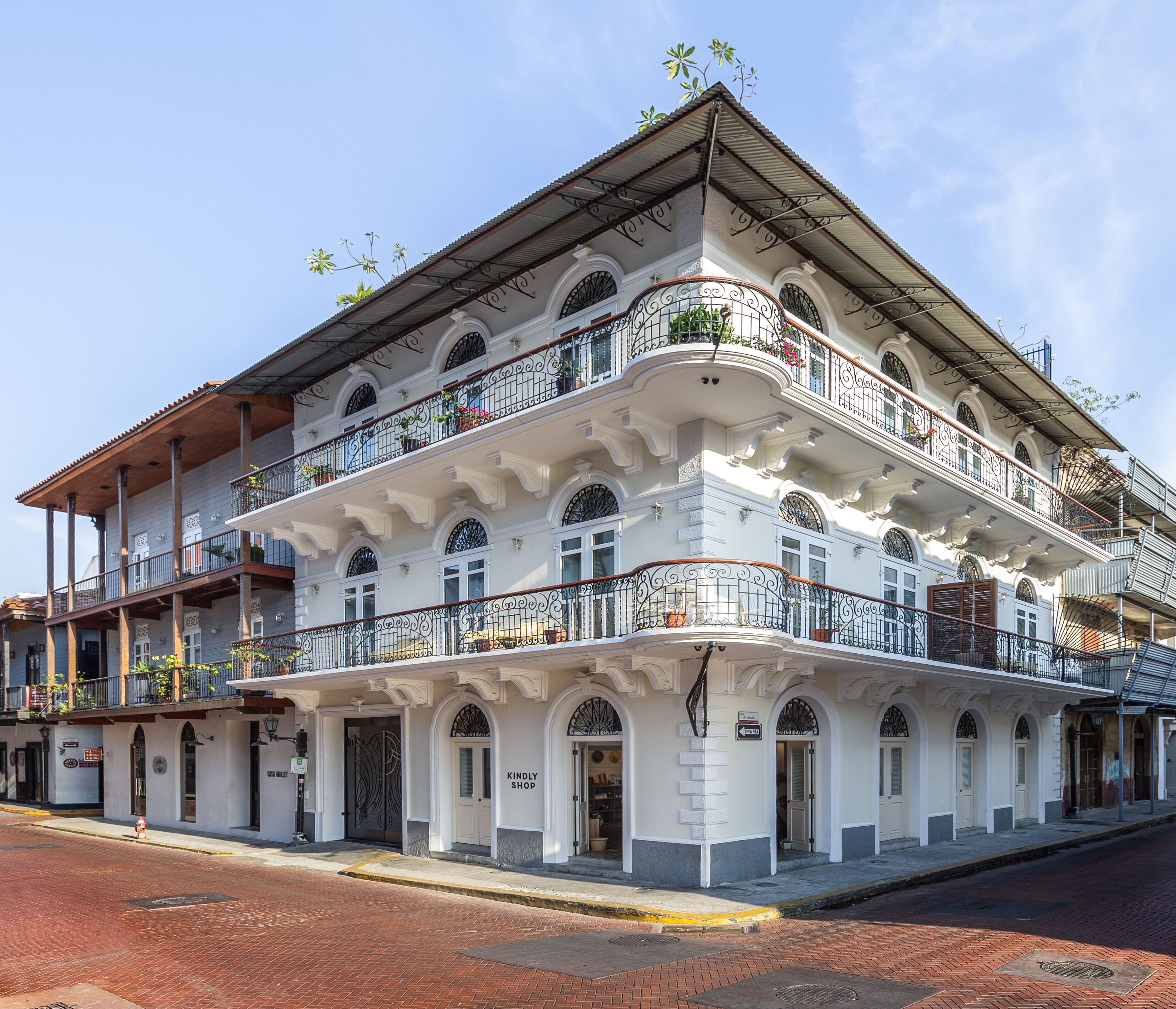 A multi-story building with a white facade, ornate balconies, and a ground-level shop.