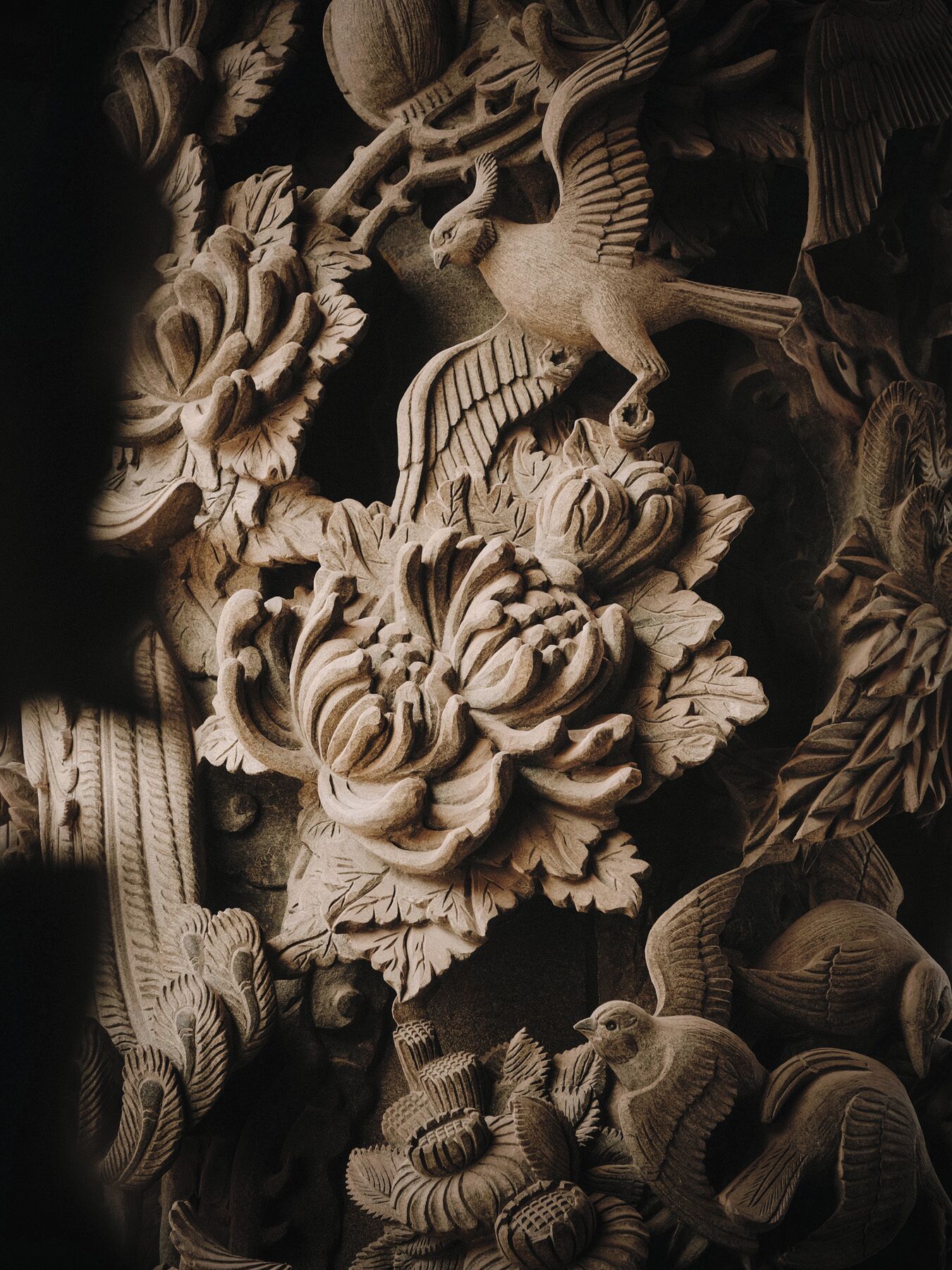 Een gedetailleerde steensculptuur met ingewikkelde bloem- en vogelmotieven.