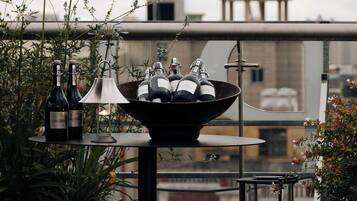 A rooftop terrace with a table holding wine bottles, a candle, and a lantern.