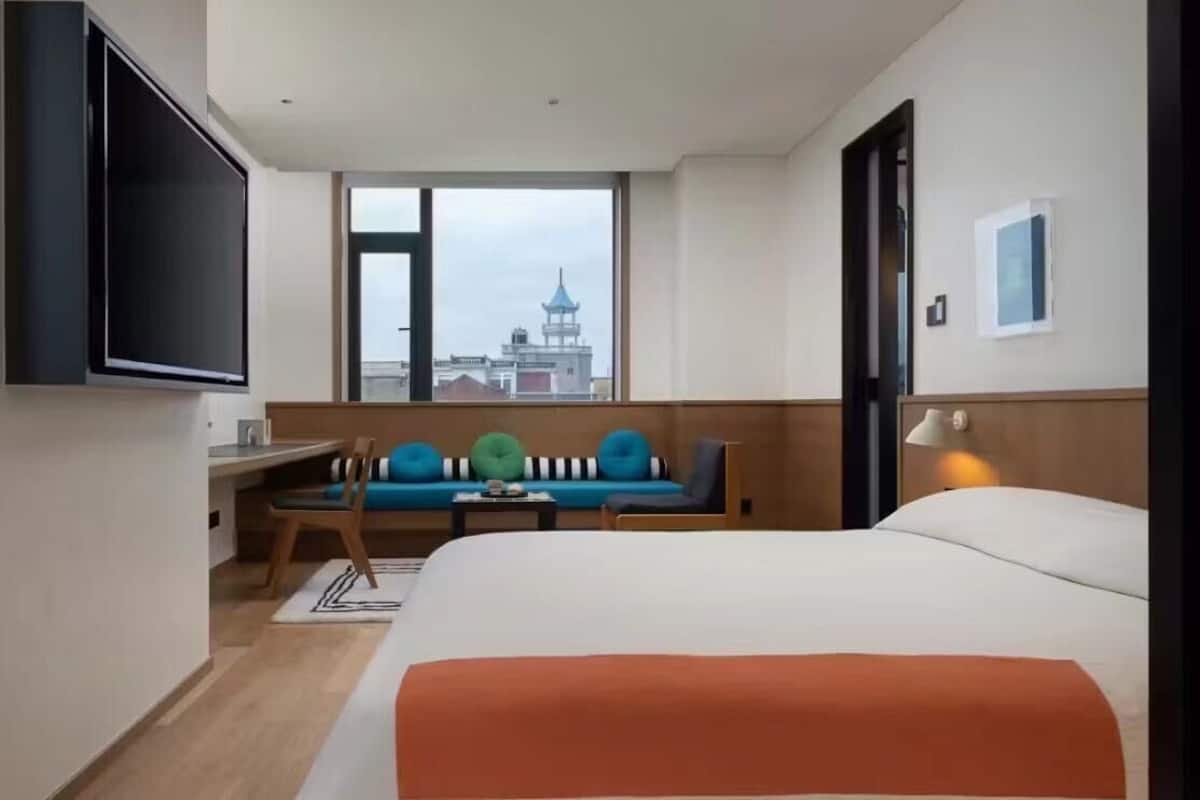 Hotellihuone, jossa on sänky, työpöytä, tuoli, sohva, televisio ja ikkuna, josta on näkymä tornille.