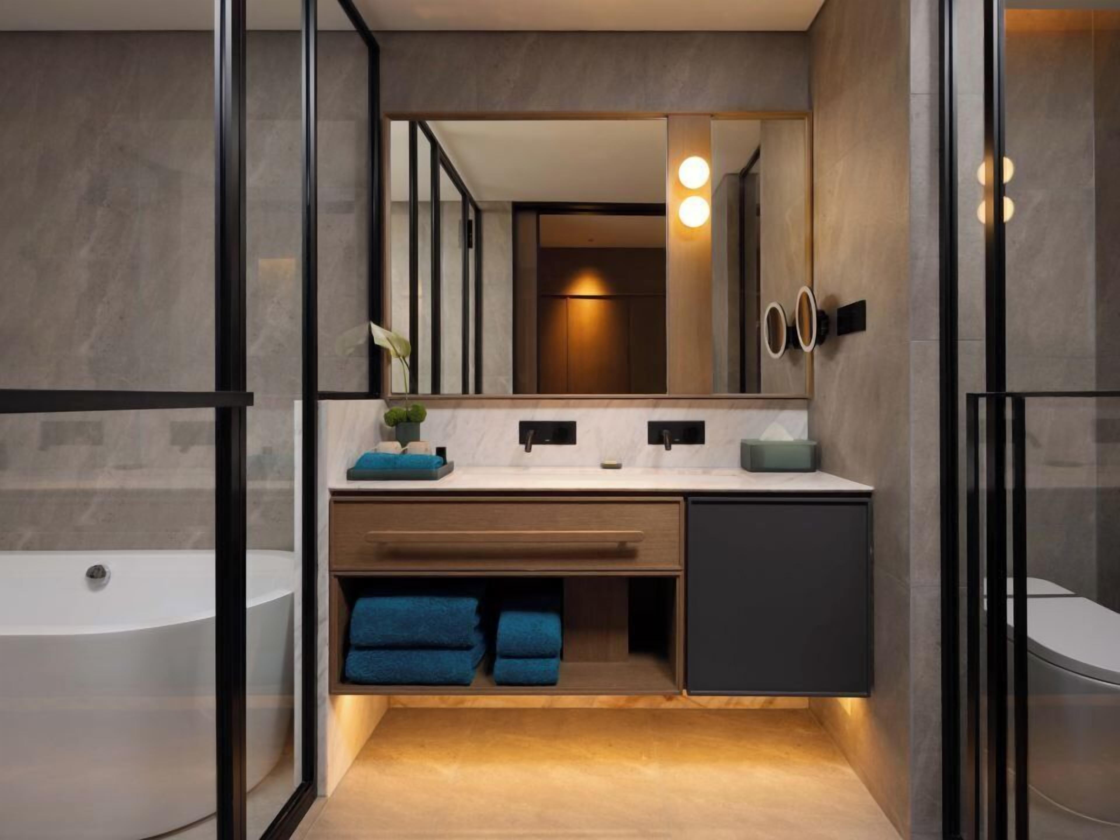 Un baño moderno con bañera, tocador con espejo y barra para toallas.