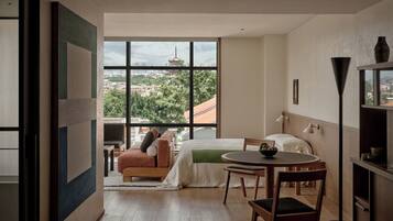 A modern hotel room with a large window, a bed, a round table, and a chair.