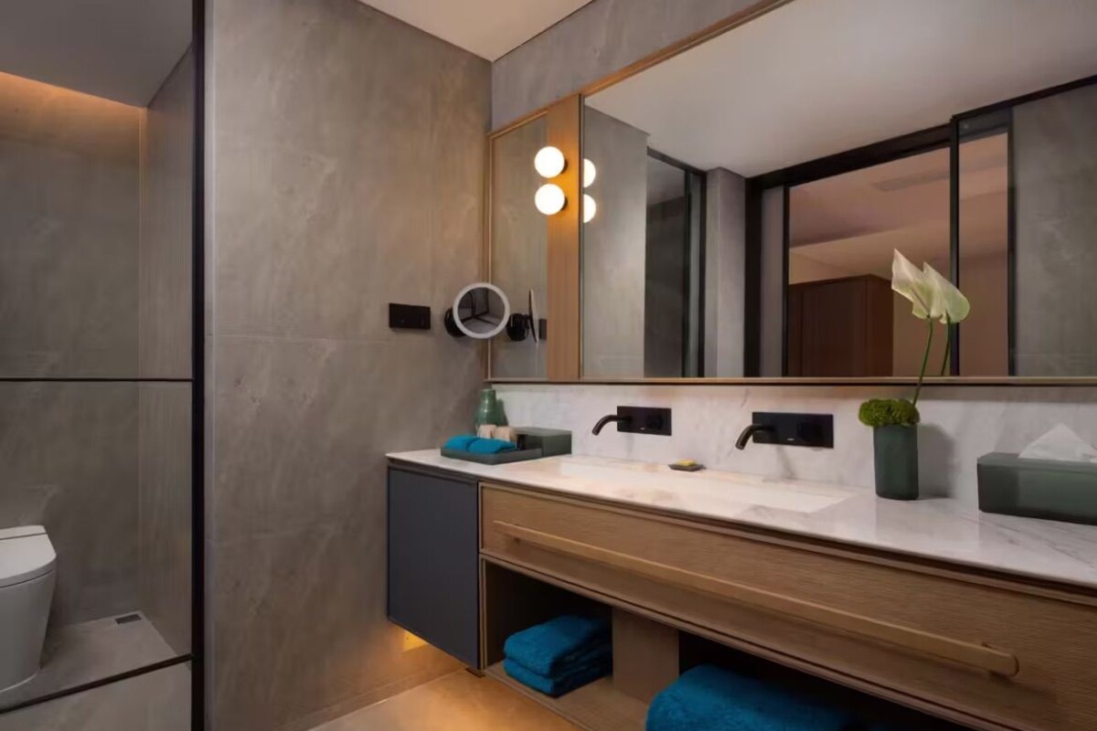 A modern bathroom with a large mirror, a sink, and a toilet.