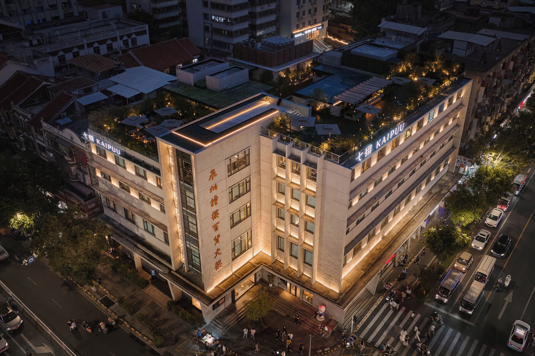 A multi-story hotel with a rooftop garden, a prominent entrance, and a well-lit facade.