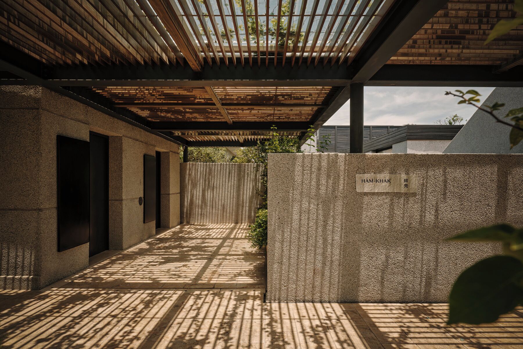 A modern architectural design with a concrete wall, a wooden ceiling, and a metal door.