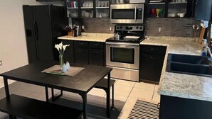 Uma cozinha moderna com armários pretos, eletrodomésticos de aço inoxidável e bancada de granito.