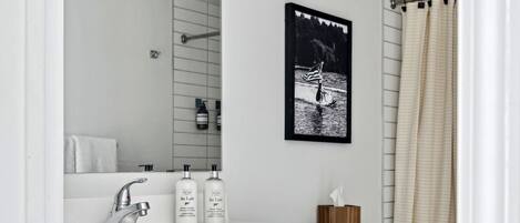 Et moderne badeværelse med et hvidt toiletbord, et stort spejl, et toilet og en badeforhæng.