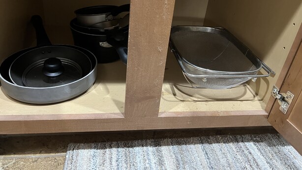 Une cuisine équipée d’une cuisinière, de casseroles et d’une passoire en métal.
