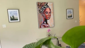 Een kamer met een groot schilderij aan de muur, een klein potplantje en een bureau met een computer.
