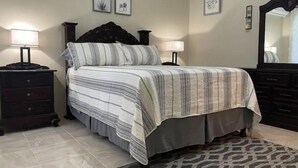 Een slaapkamer met een bed, twee nachtkastjes, een dressoir en een spiegel.
