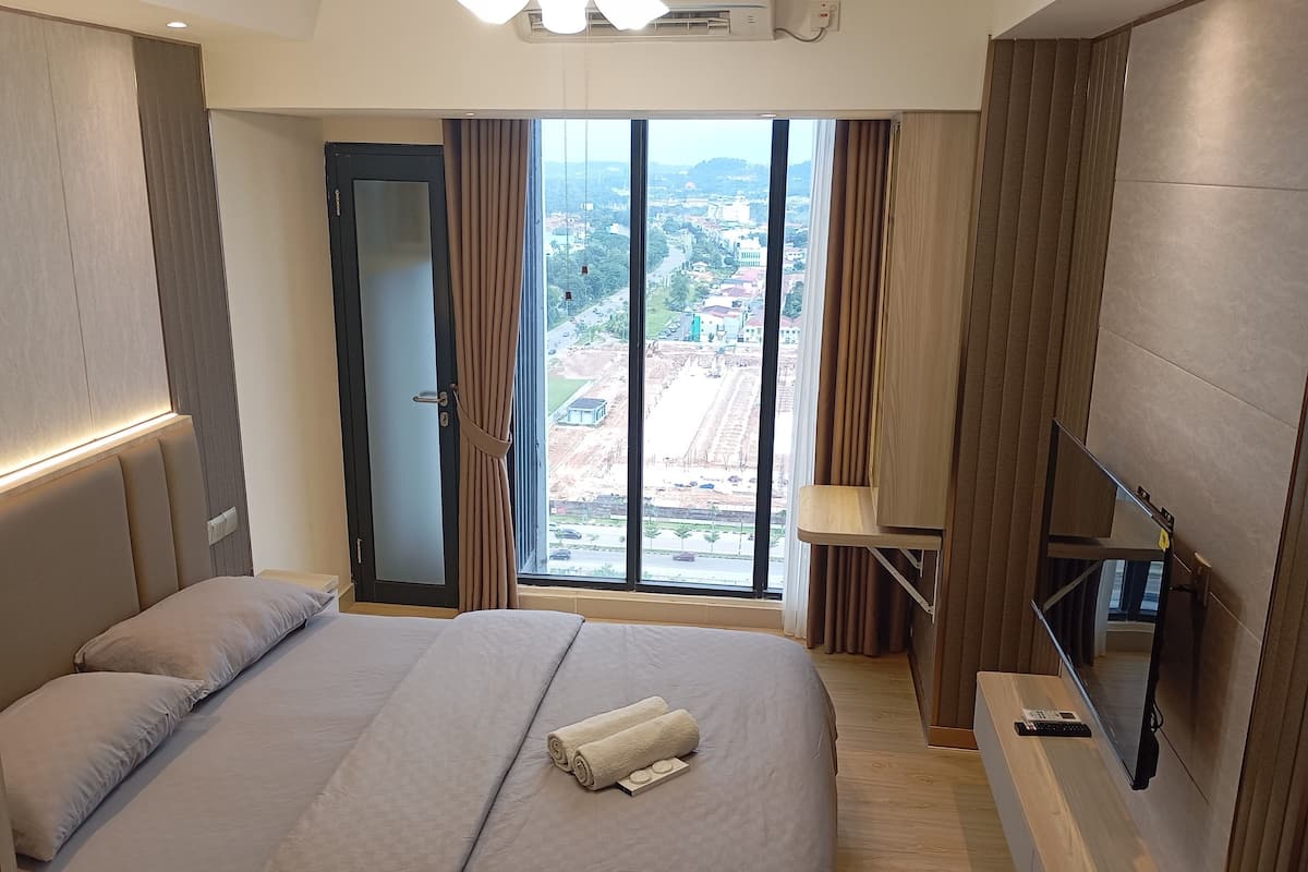 Ein modernes Hotelzimmer mit einem großen Bett, einem Fernseher und Blick auf eine Stadtlandschaft durch das Fenster.