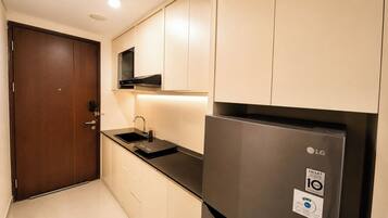 A compact kitchen with a stainless steel refrigerator, a microwave, and a sink.