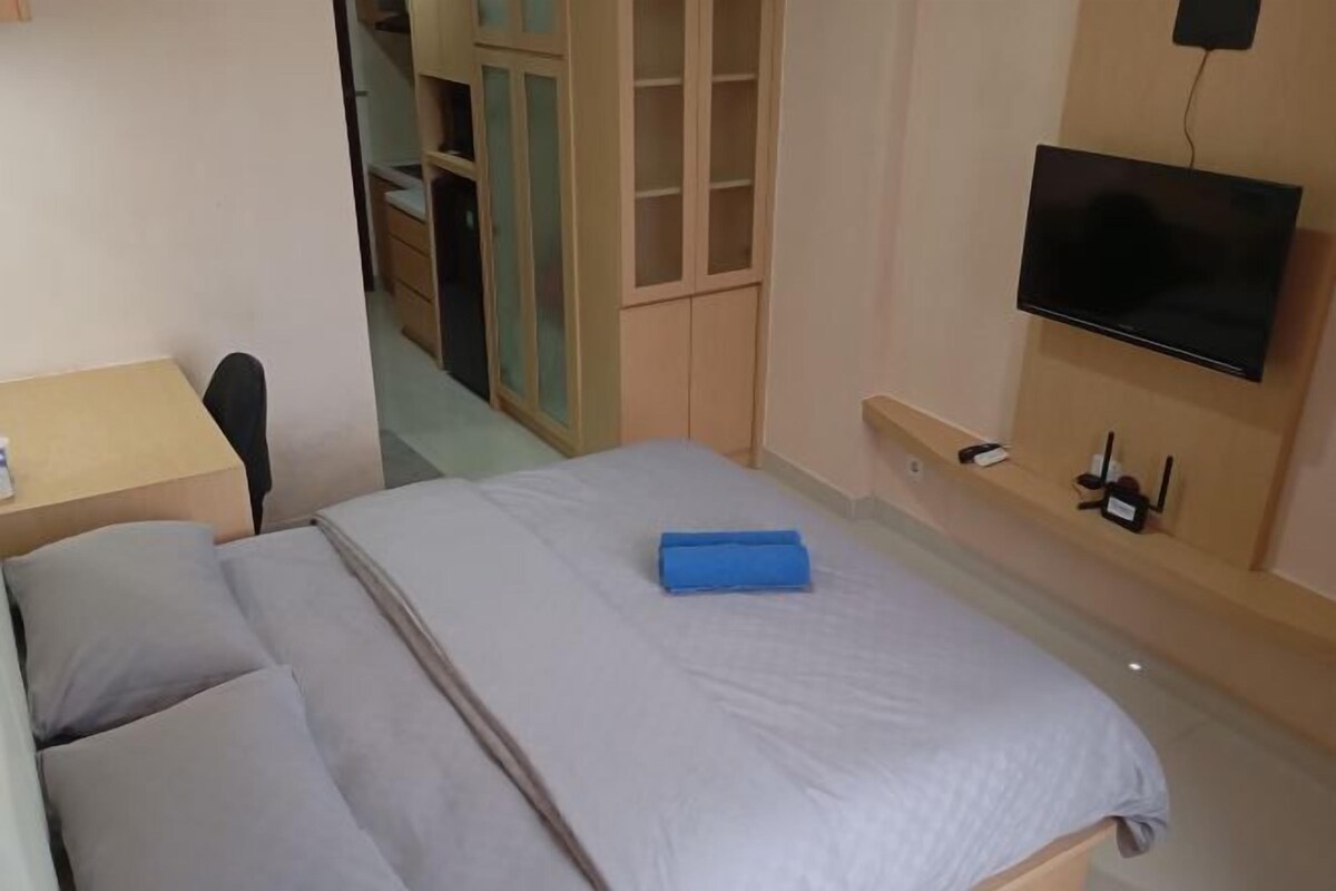 A bedroom with a bed, a TV mounted on the wall, and a wardrobe.