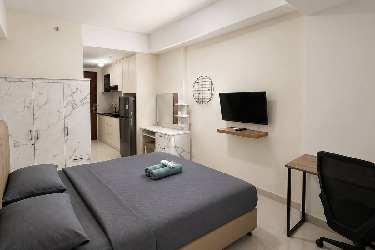 Ein Schlafzimmer mit Bett, Schreibtisch, Stuhl, Fernseher und Kleiderschrank.