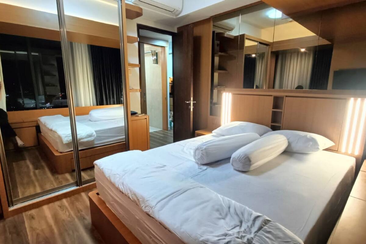 Ein modernes Hotelzimmer mit einem großen Bett, einem Spiegel und einem Kleiderschrank.