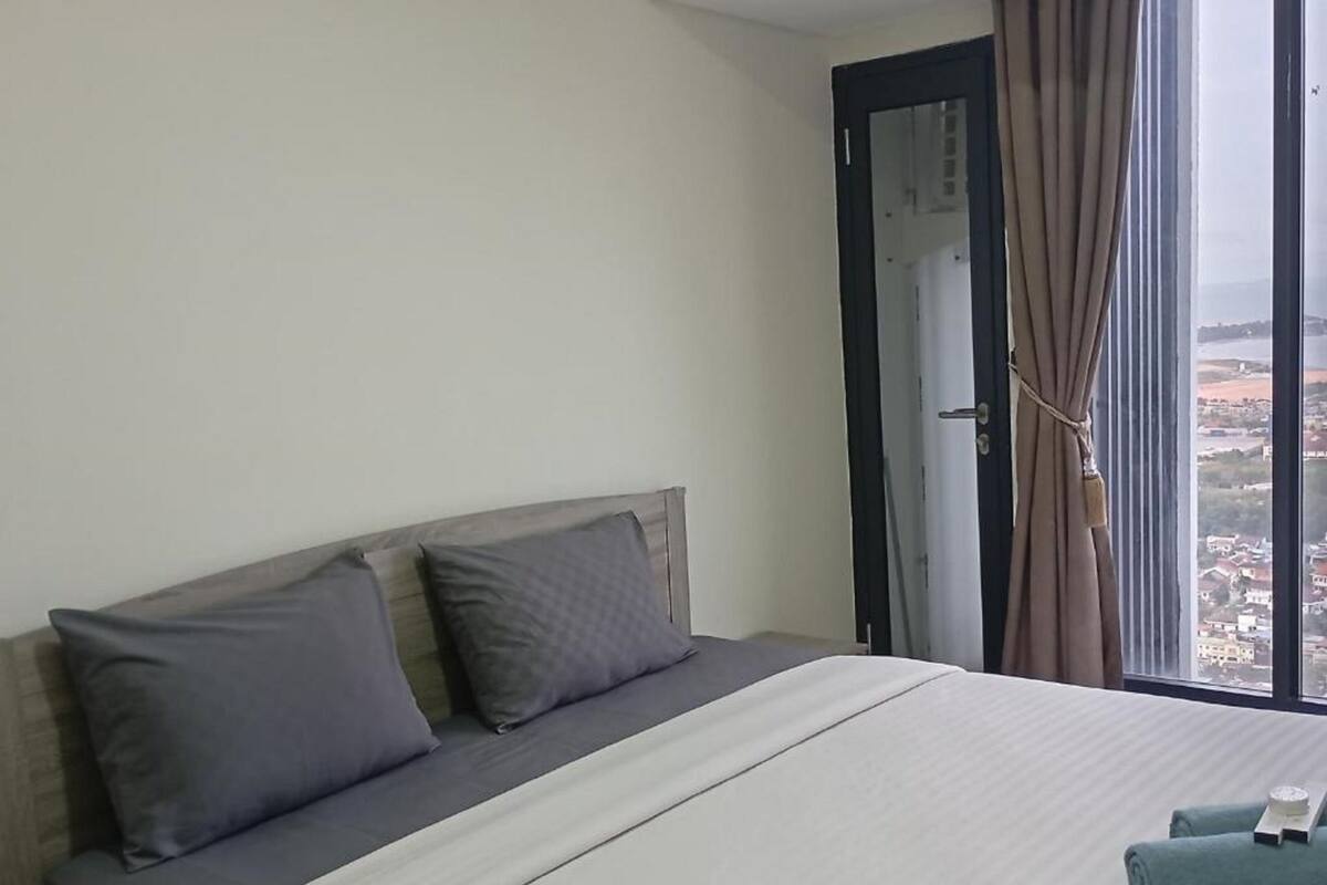 Ein Hotelzimmer mit Bett, einem Fenster mit Vorhängen und Blick auf die Stadt.