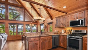 A spacious kitchen with wooden cabinets, a stainless steel stove, and a large window overlooking a scenic view.