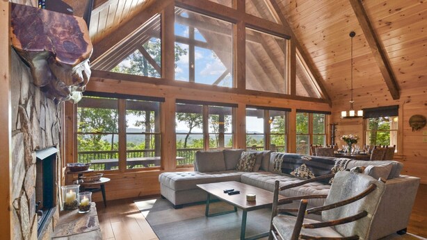 A spacious living area with a large sectional sofa, a wooden coffee table, and a rustic fireplace.