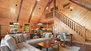 A spacious living room with a large sectional sofa, a wooden coffee table, and a staircase leading to an upper level.