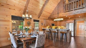 A spacious wooden cabin with a large dining area, kitchen, and bar.