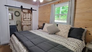 A bedroom with a bed, a wardrobe, a window, and a door.