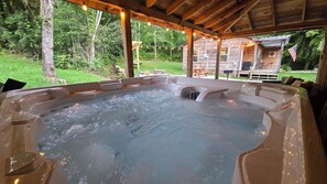 A hot tub under a wooden pergola with a view of a wooden cabin and a grassy yard. - Creekside Cottage –Hot Tub!, Pool Table, Firepit & Pet-Friendly in the Nantahala (Topton)