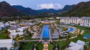 Un complexe hôtelier doté d’une piscine centrale, de plusieurs bâtiments abritant les chambres et situé dans un cadre montagneux.