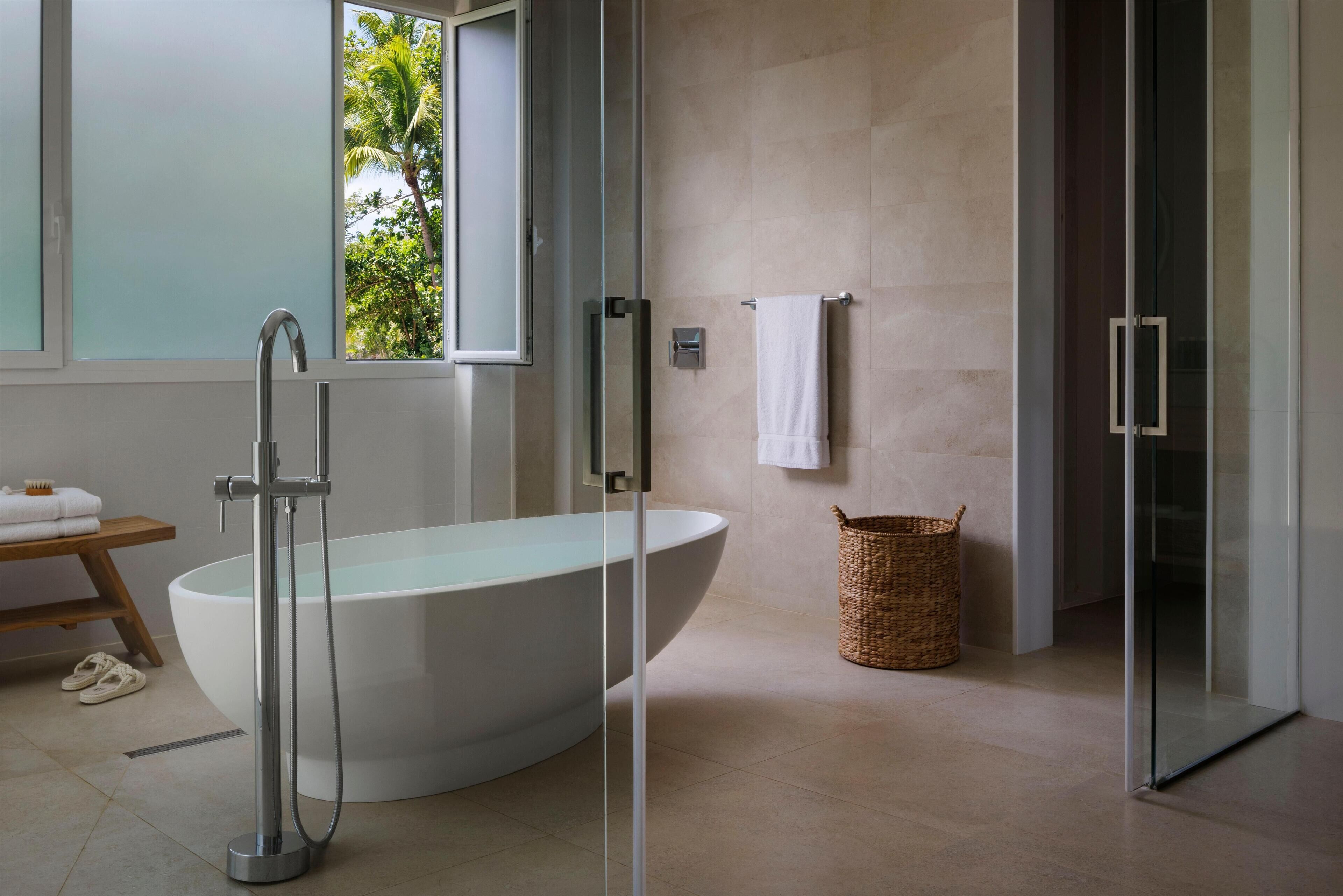 A modern bathroom with a freestanding bathtub, a glass shower enclosure, and a wicker basket.