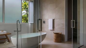 A modern bathroom with a freestanding bathtub, a glass shower enclosure, and a wicker basket.